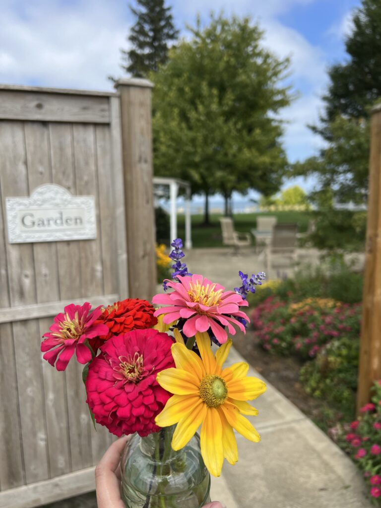 Floral bouquet in hand, looking at the Garden Cottage patio with the lake in the background